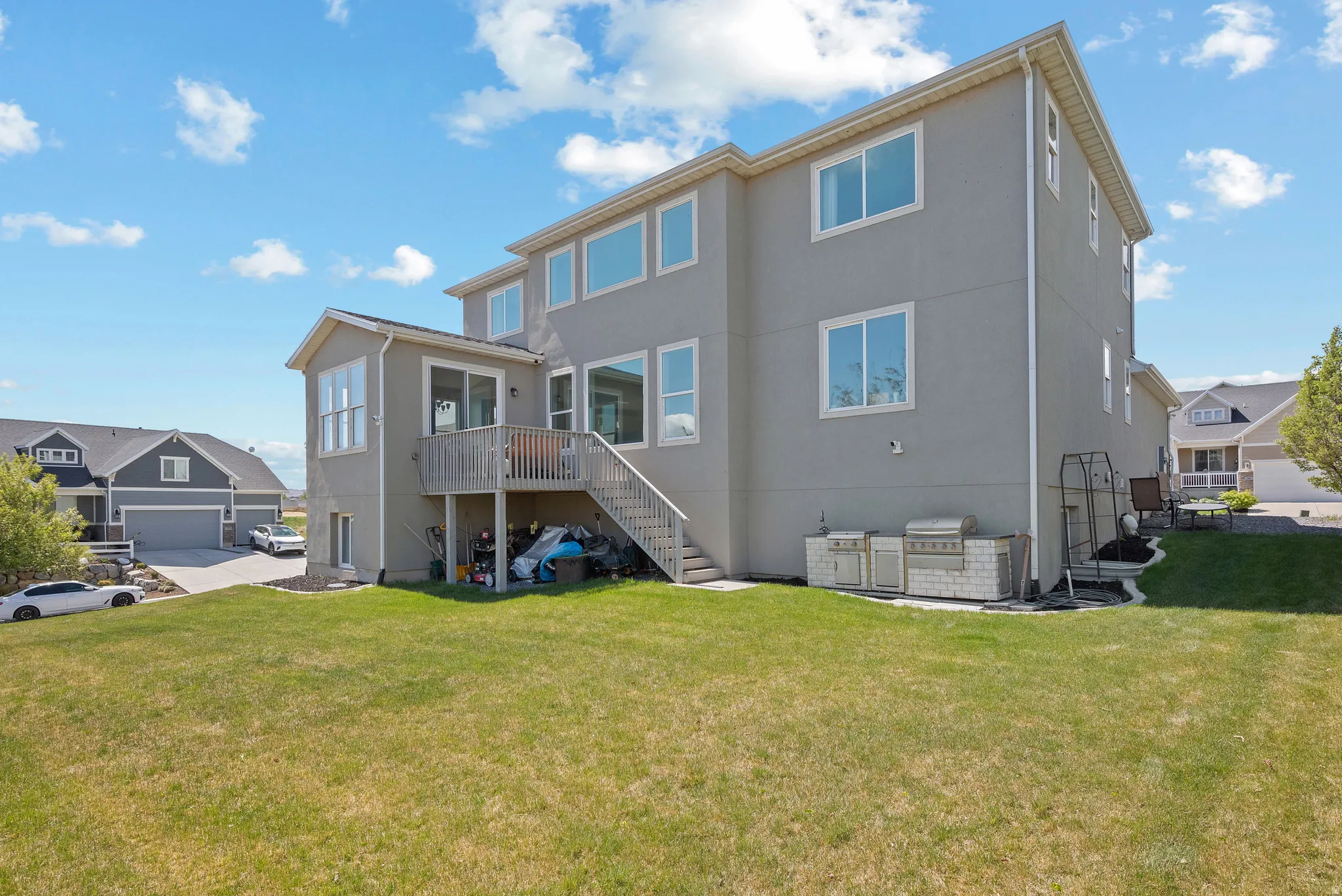 Back of house with stucco siding, a yard, a deck, and a patio area