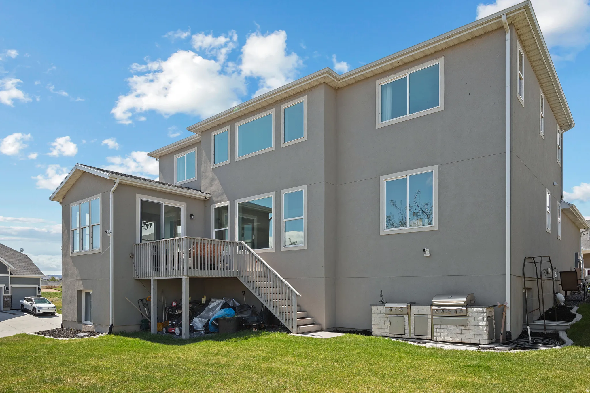 Back of property with stucco siding, a wooden deck, a lawn, and exterior kitchen