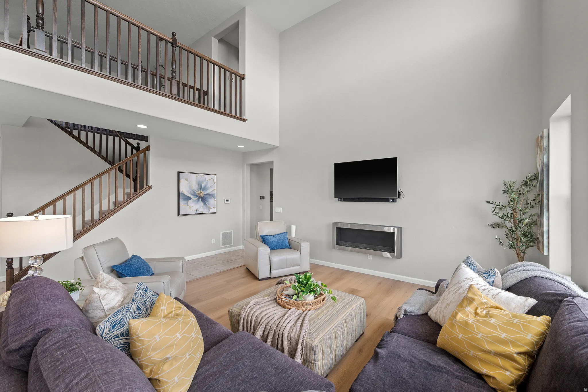 Living area featuring a gas fireplace, a high ceiling, and wood laminate floors