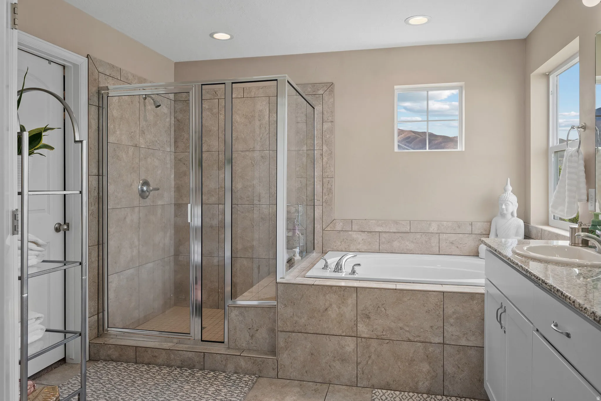 Bathroom featuring vanity, a glass shower , a soaker tub, recessed lighting, and light tile patterned floors
