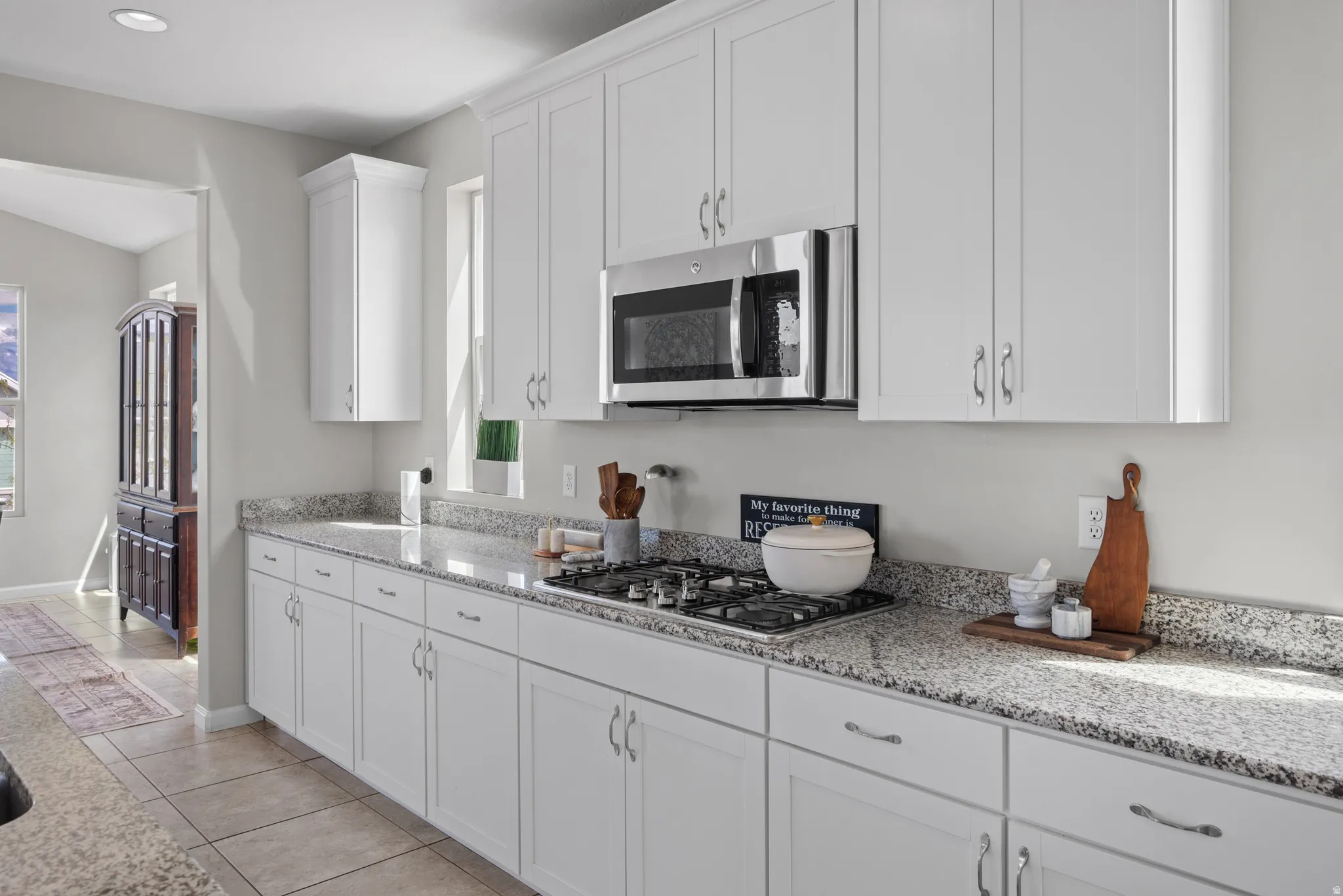 Kitchen featuring light stone countertops, white cabinetry, stainless steel appliances, and light tile patterned floors