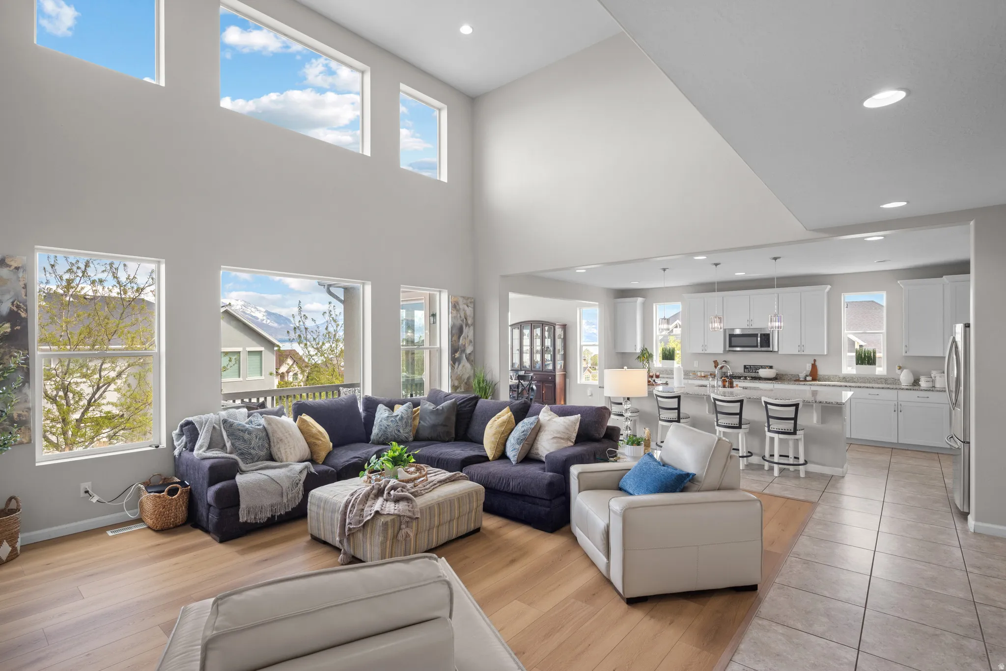 Living room featuring light laminate floors, recessed lighting, and a high ceiling