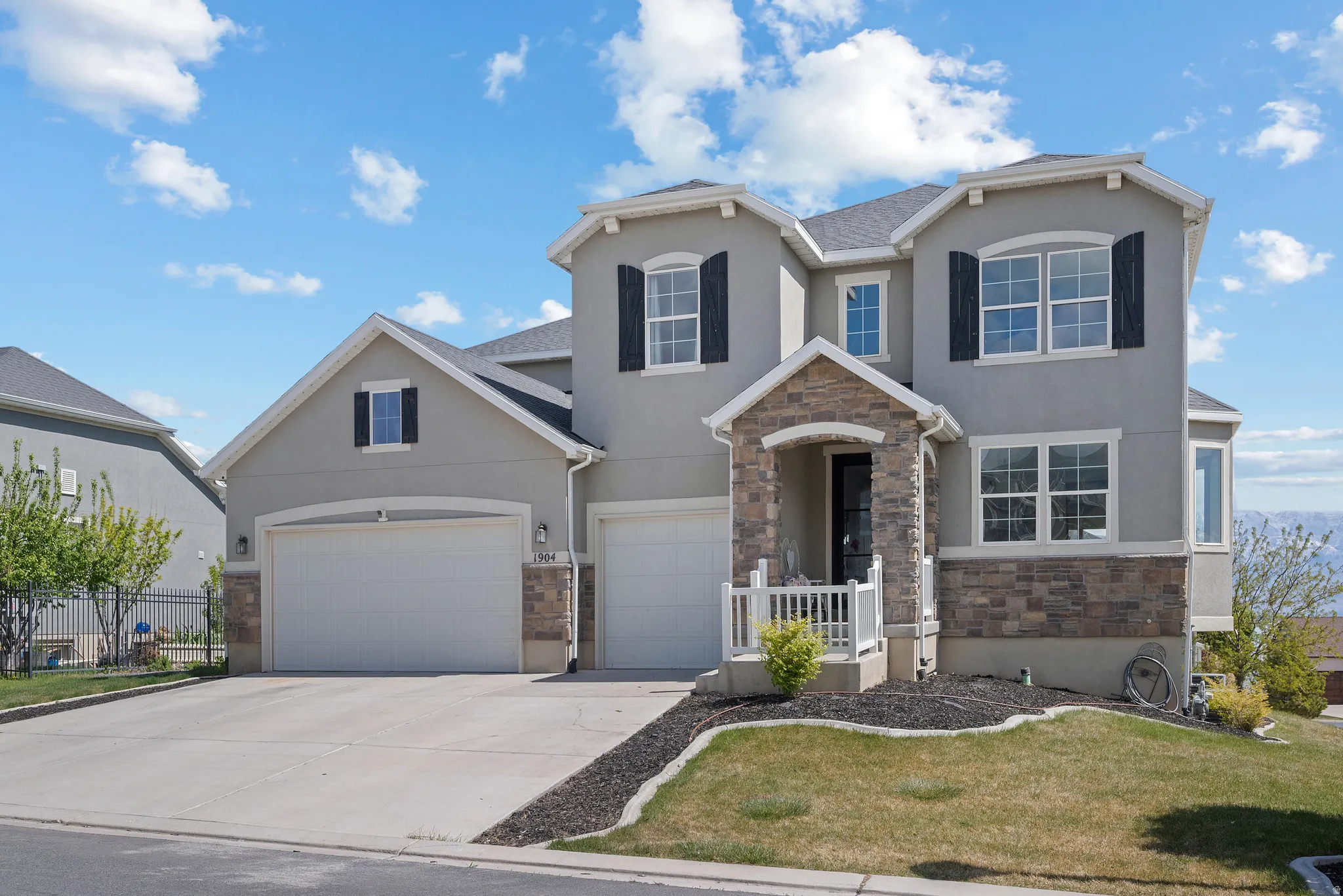 Traditional-style house with stone siding, stucco siding, driveway, an attached garage, and a front yard