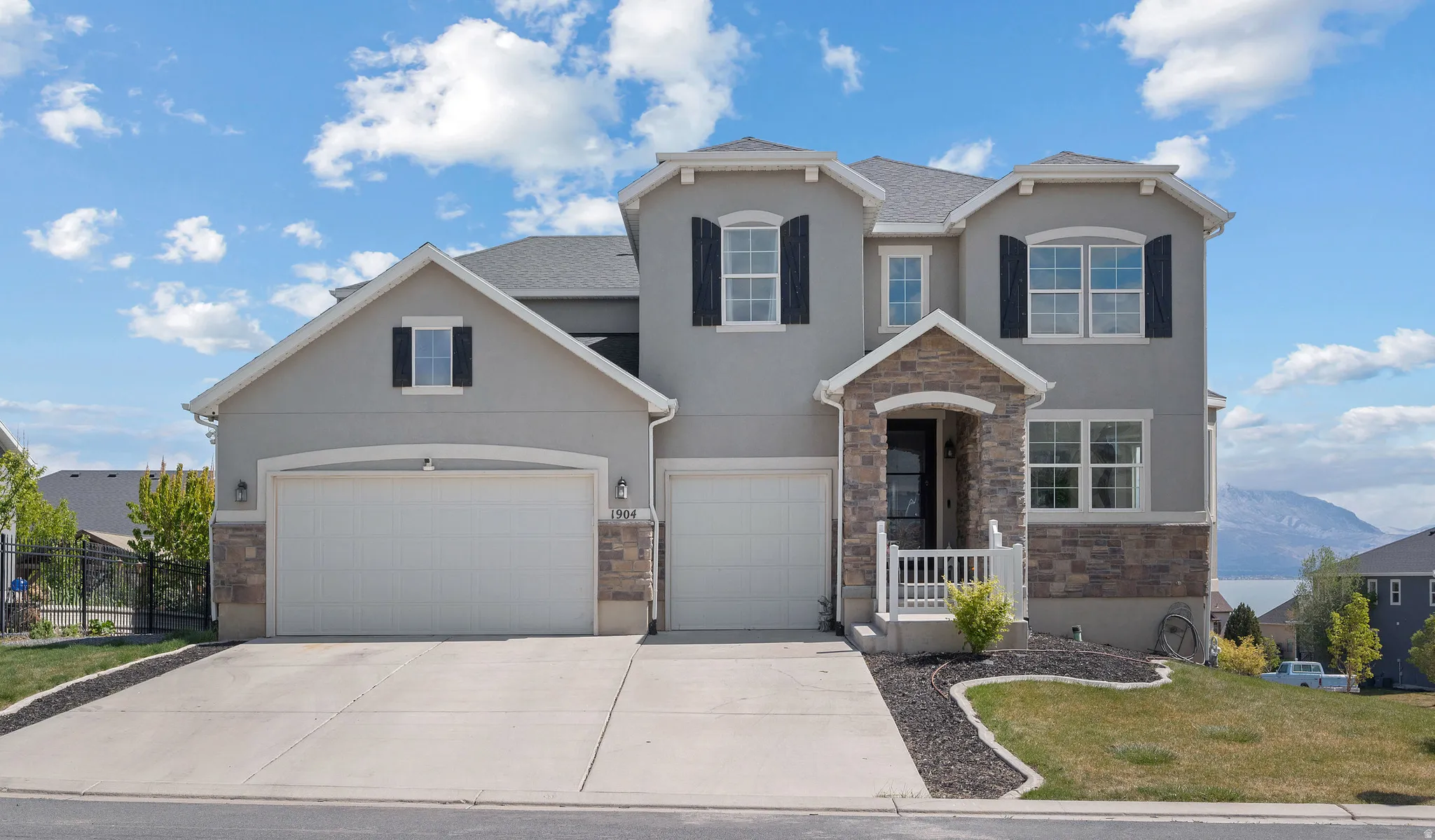 View of front of property featuring stone siding, stucco siding, concrete driveway, a garage, and a front yard