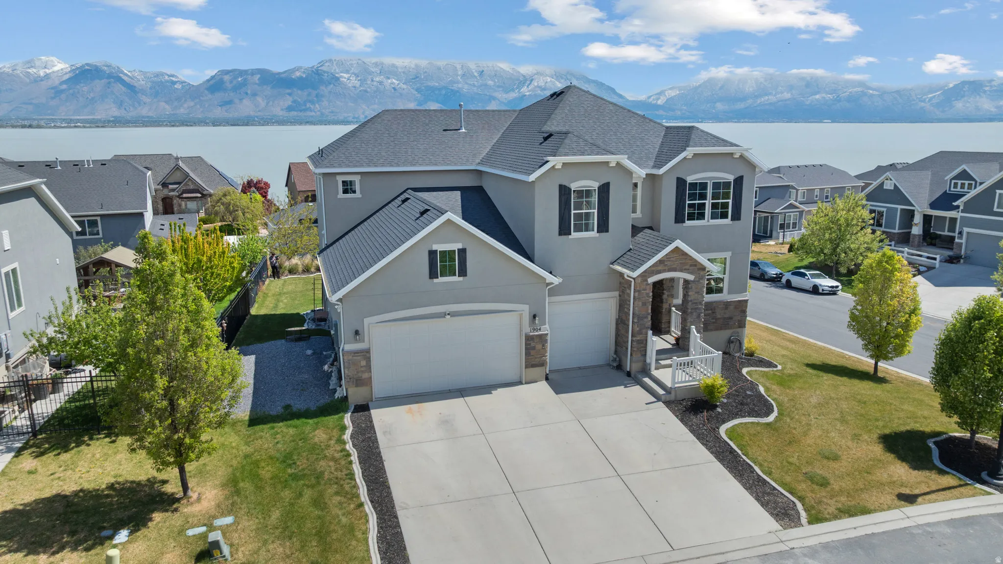 Traditional-style house featuring a residential view, a garage, concrete driveway, stucco siding, and a front yard