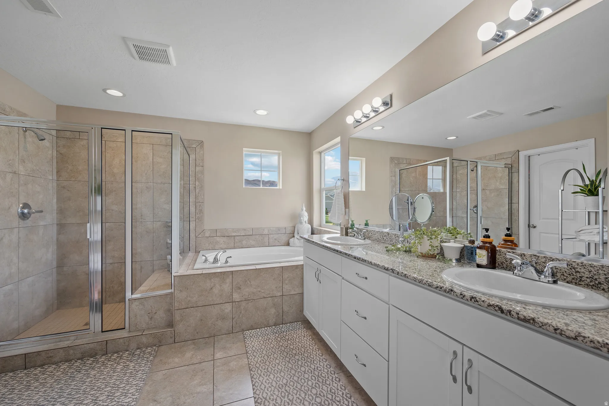 Primary Suite Bathroom with double vanity, glass shower, a garden tub, light tile patterned flooring, and recessed lighting