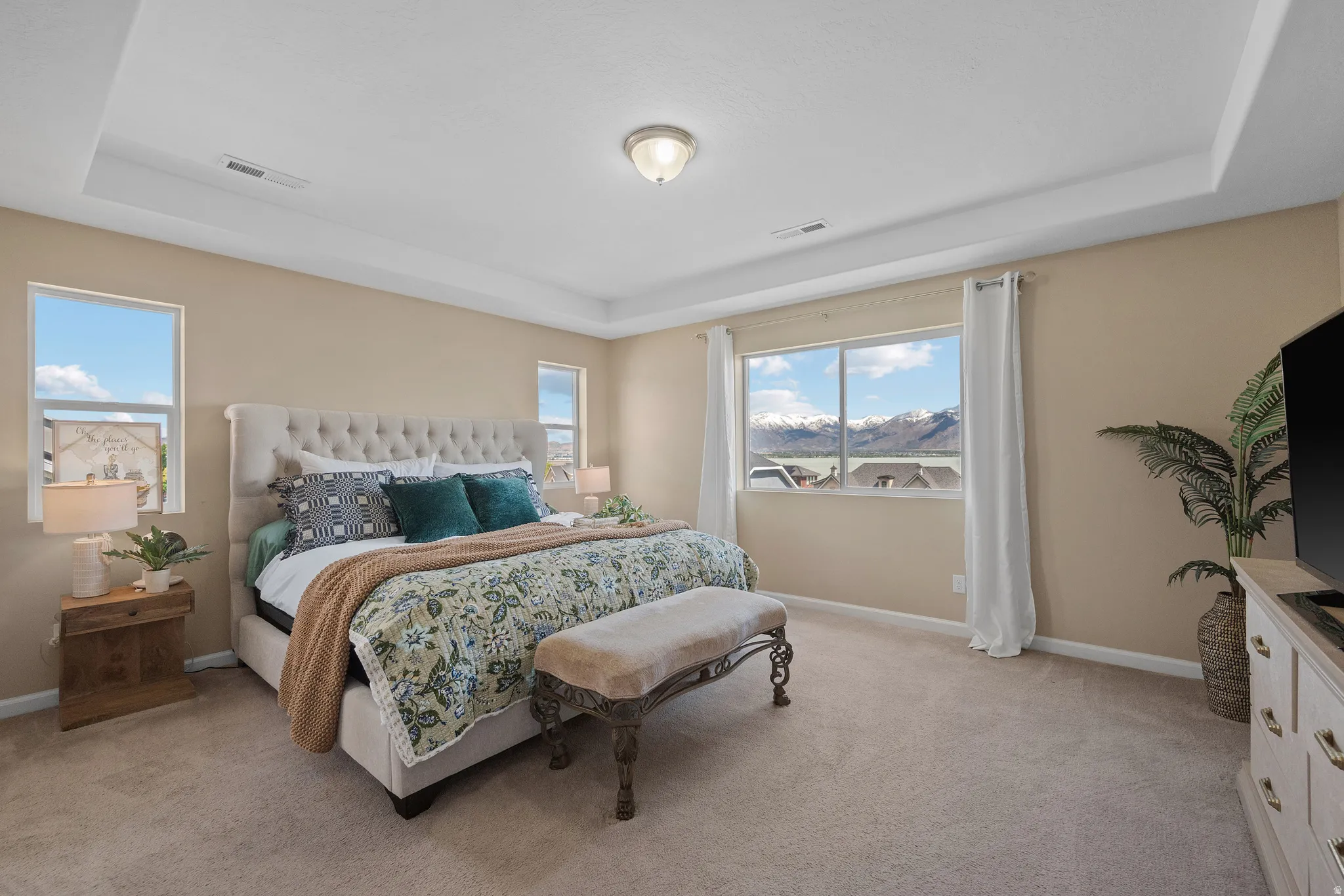 Primary Bedroom with a tray ceiling and light carpet