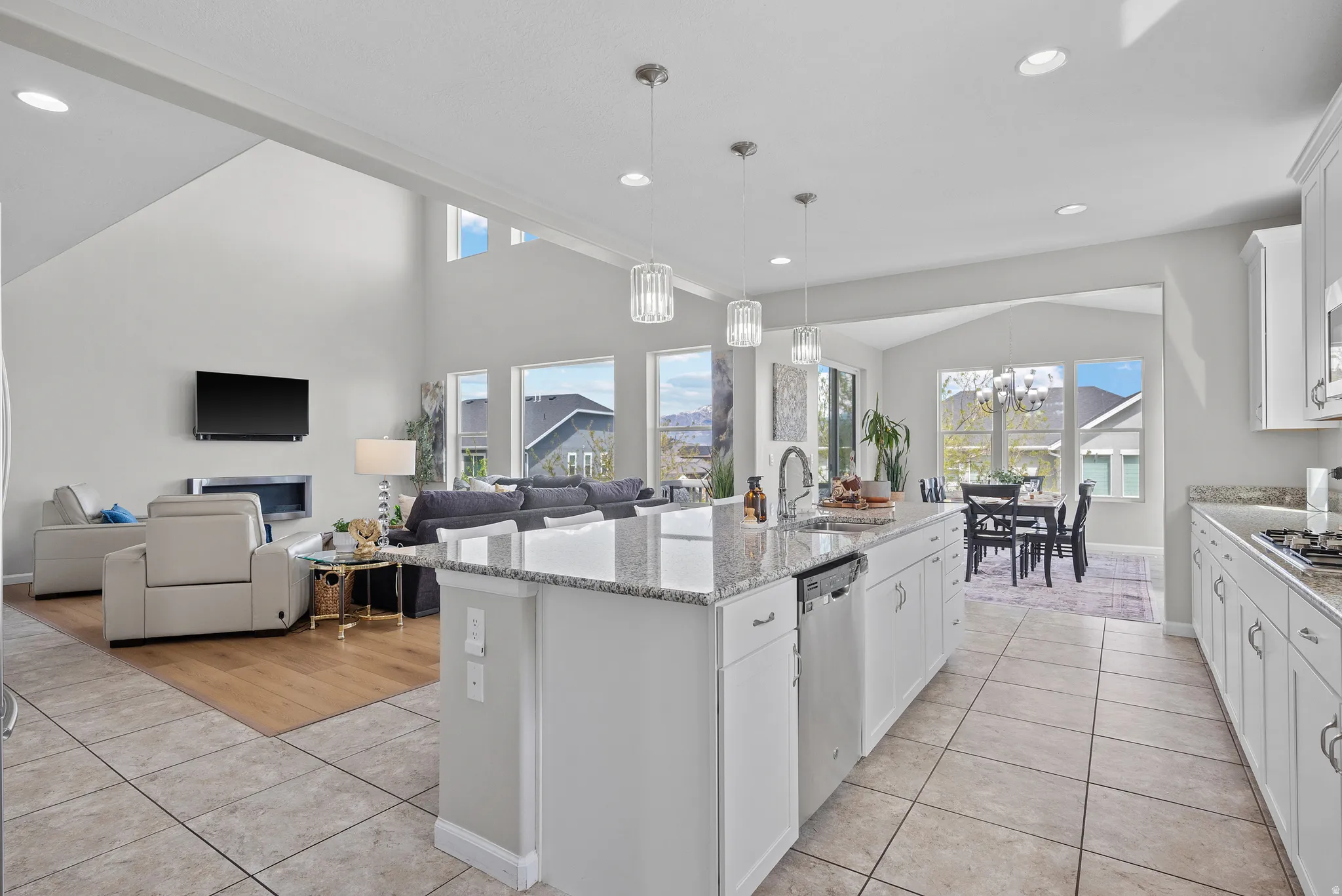 Kitchen featuring white cabinetry, light tile patterned floors, a kitchen island with sink, open floor plan, and lofted ceiling
