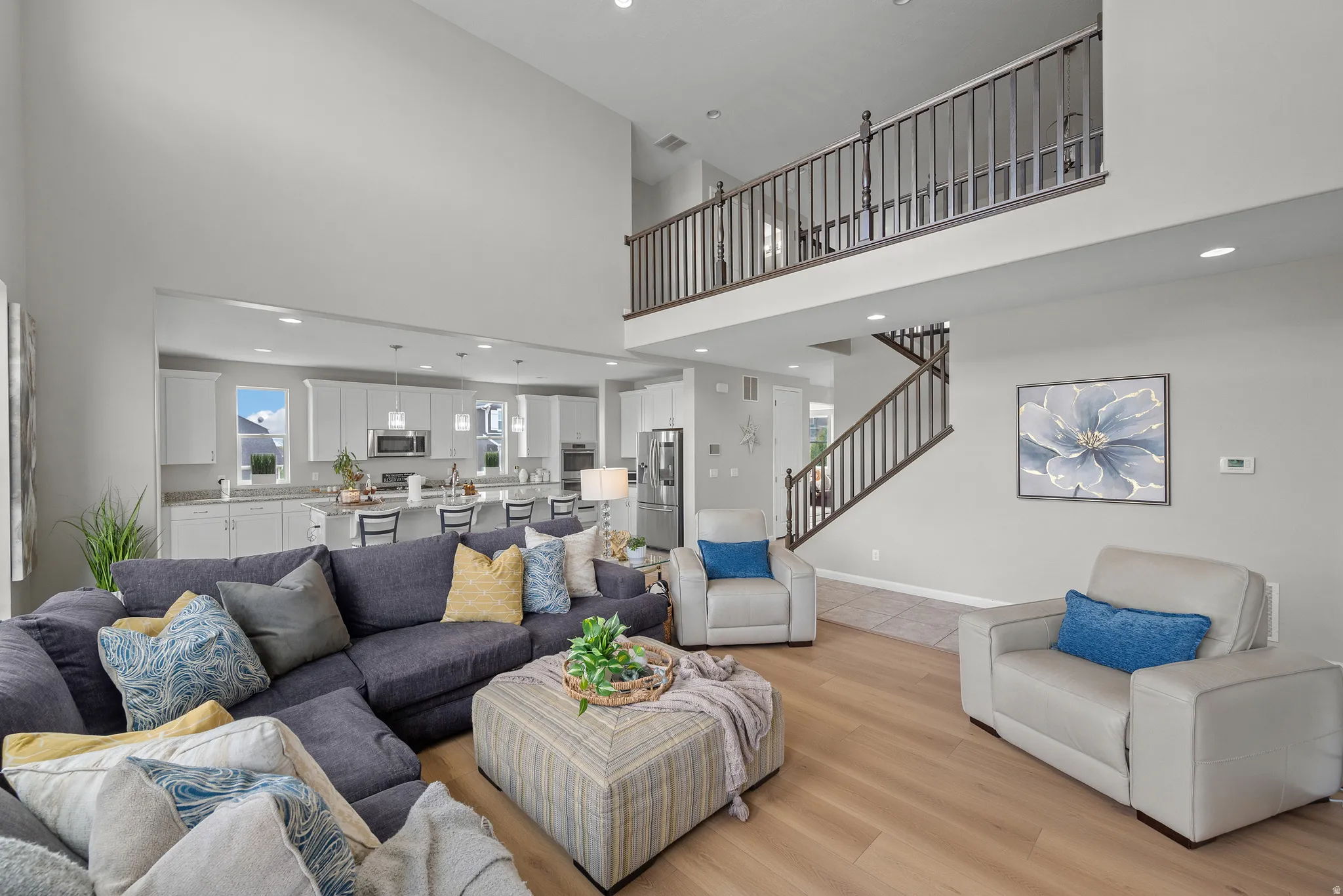 Living room with recessed lighting, light laminate flooring, and a high ceiling