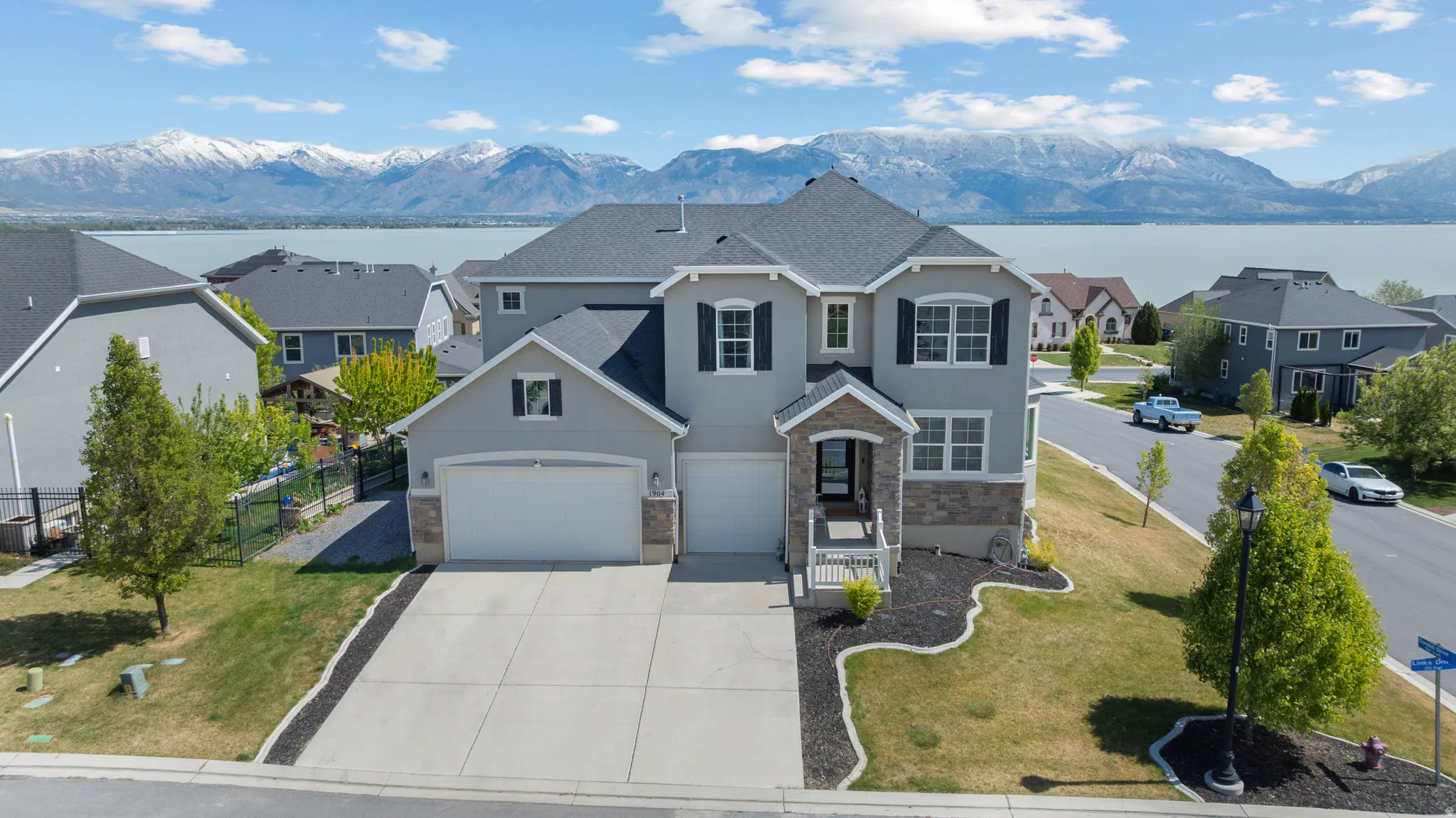 Traditional-style home featuring stucco siding, a water and mountain view, concrete driveway, a residential view, and stone siding