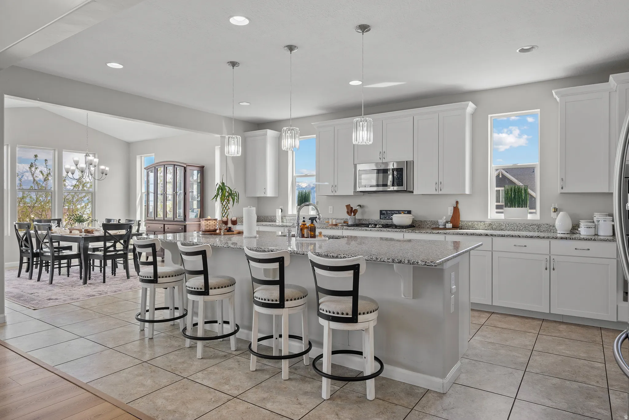 Kitchen featuring an island with sink, white cabinets, light stone countertops, a kitchen bar, and lofted ceiling