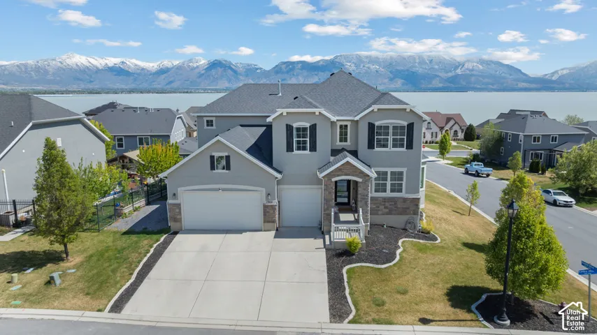 Traditional-style home featuring stucco siding, a water and mountain view, concrete driveway, a residential view, and stone siding