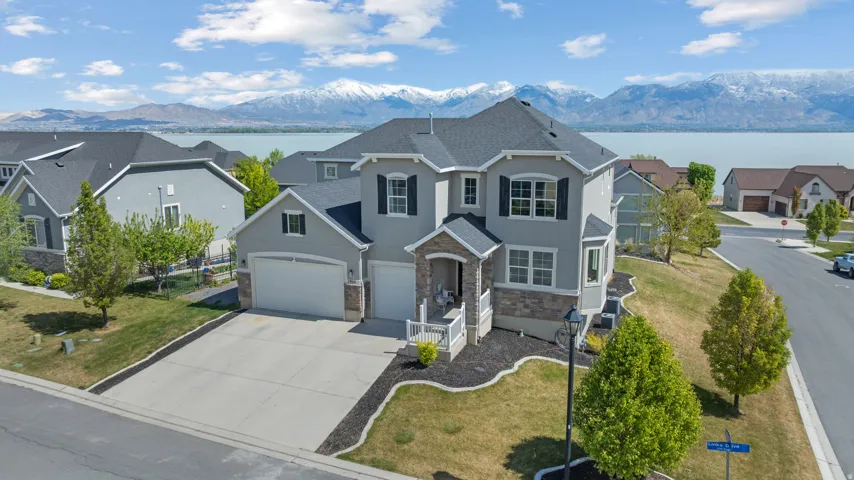 Traditional-style house featuring a water and mountain view, driveway, a front yard, stucco siding, and stone siding