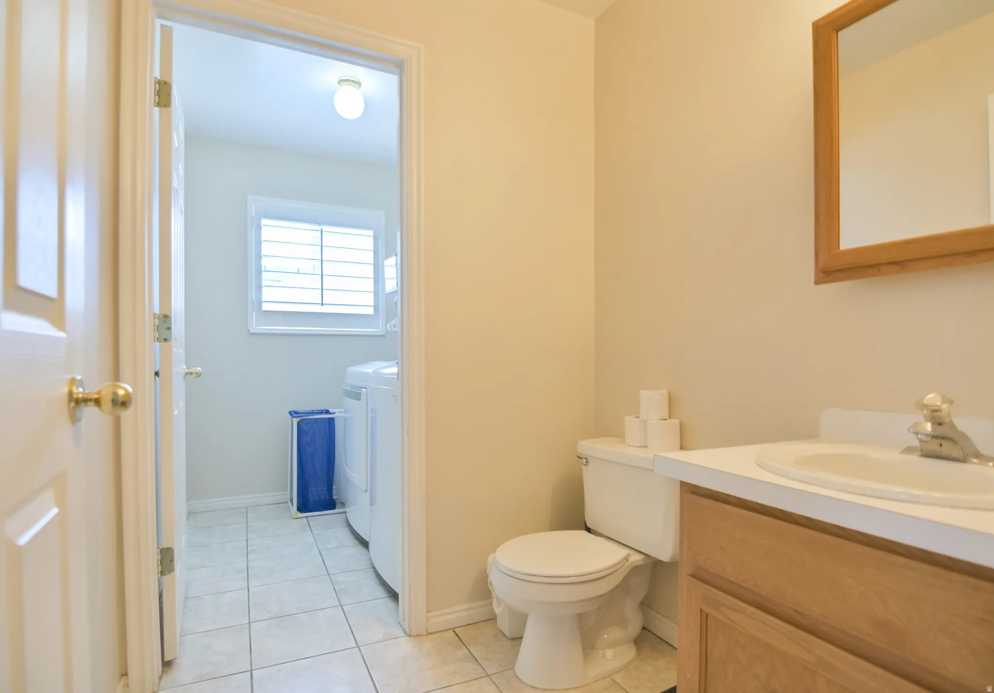 Bathroom with vanity, independent washer and dryer, and light tile patterned floors