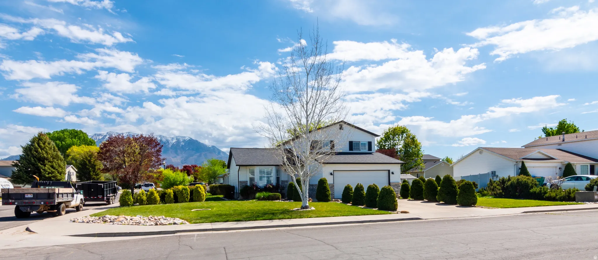 Traditional-style house featuring a front lawn, a residential view, driveway, and a garage