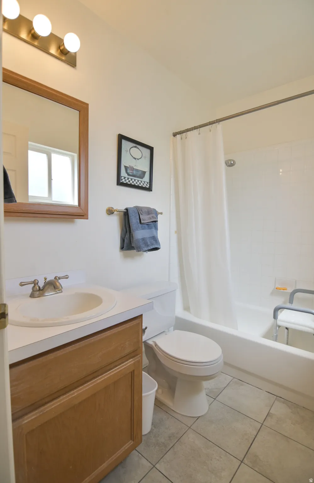 Full bath featuring vanity, light tile patterned flooring, and shower / tub combo with curtain