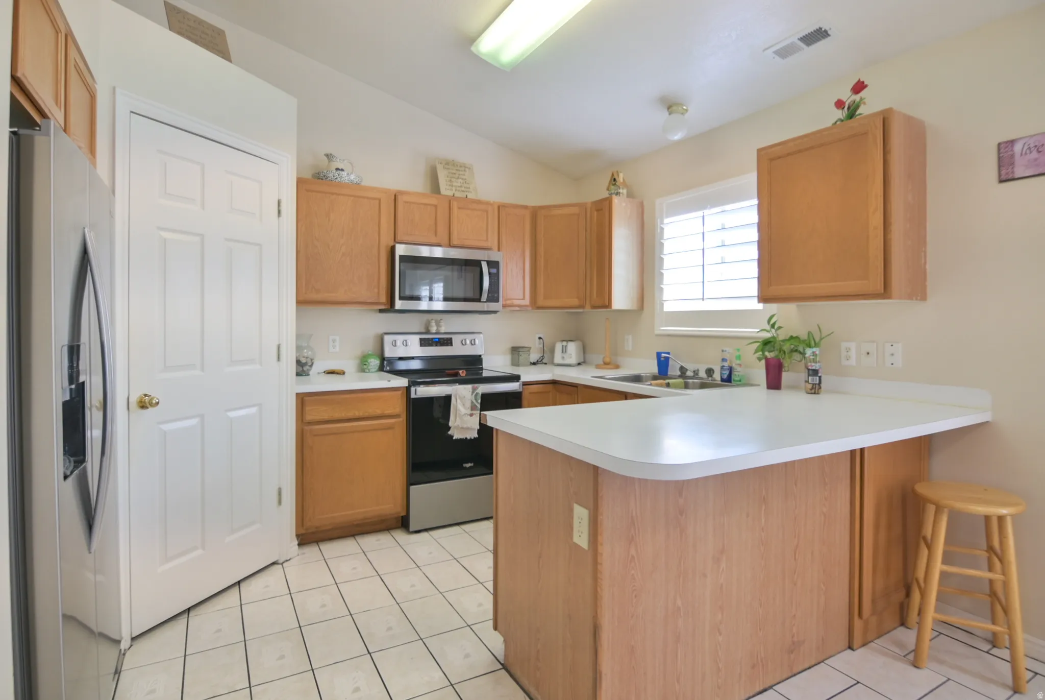 Kitchen featuring a peninsula, stainless steel appliances, lofted ceiling, light countertops, and a breakfast bar area