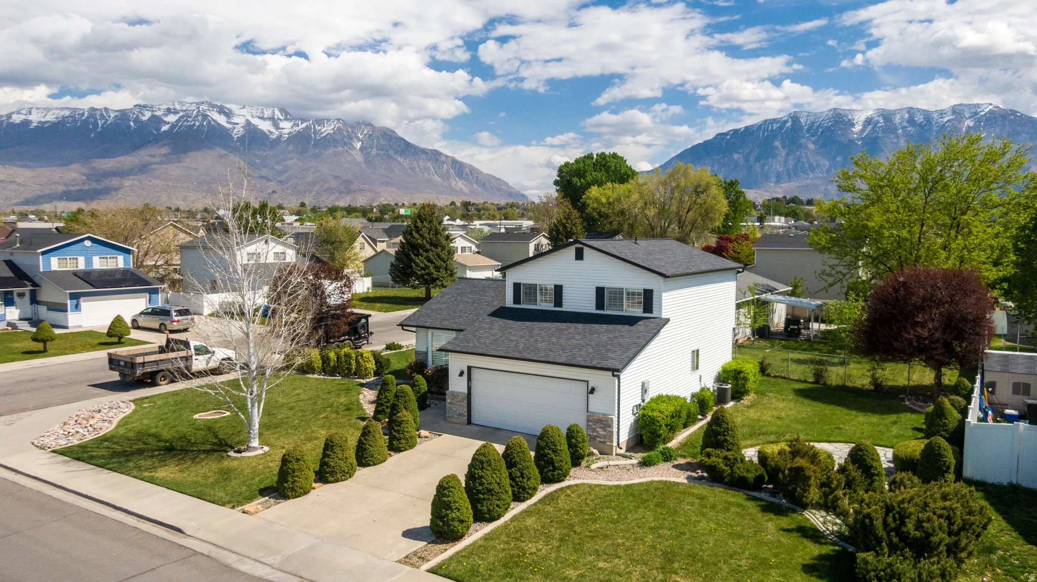 View of front of property featuring concrete driveway, a mountain view, a front yard, and stone siding