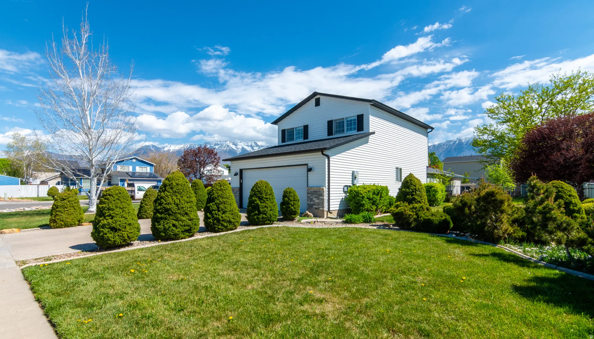 View of side of home featuring a yard, a mountain view, and a garage