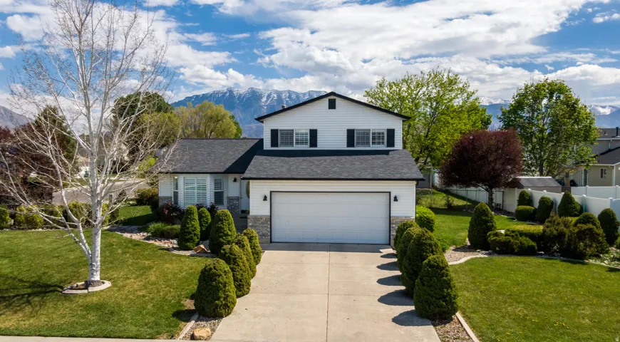 Traditional-style house featuring a front lawn, concrete driveway, an attached garage, a mountain view, and stone siding