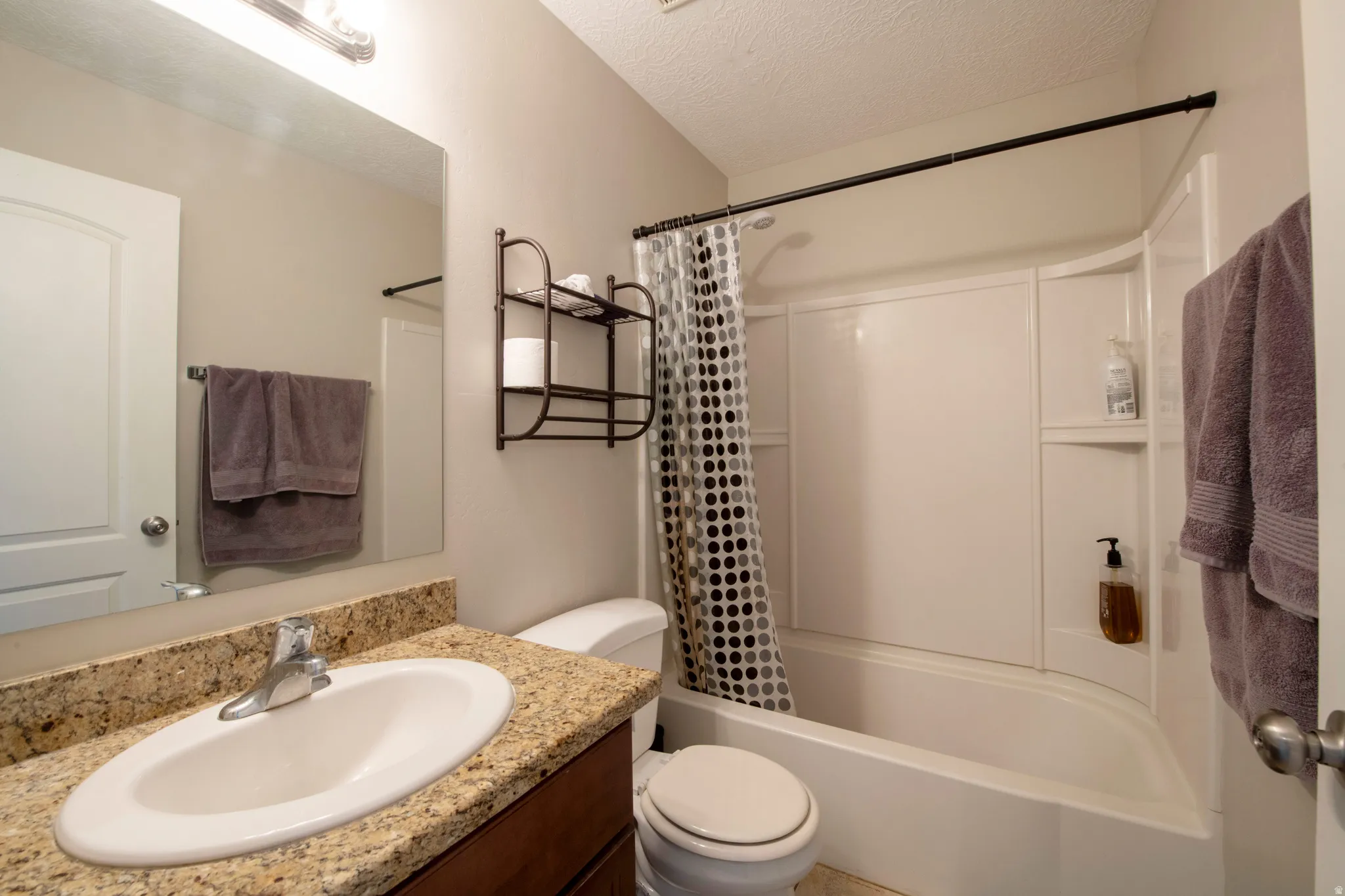 Bathroom featuring vanity, shower / bath combination with curtain, and a textured ceiling