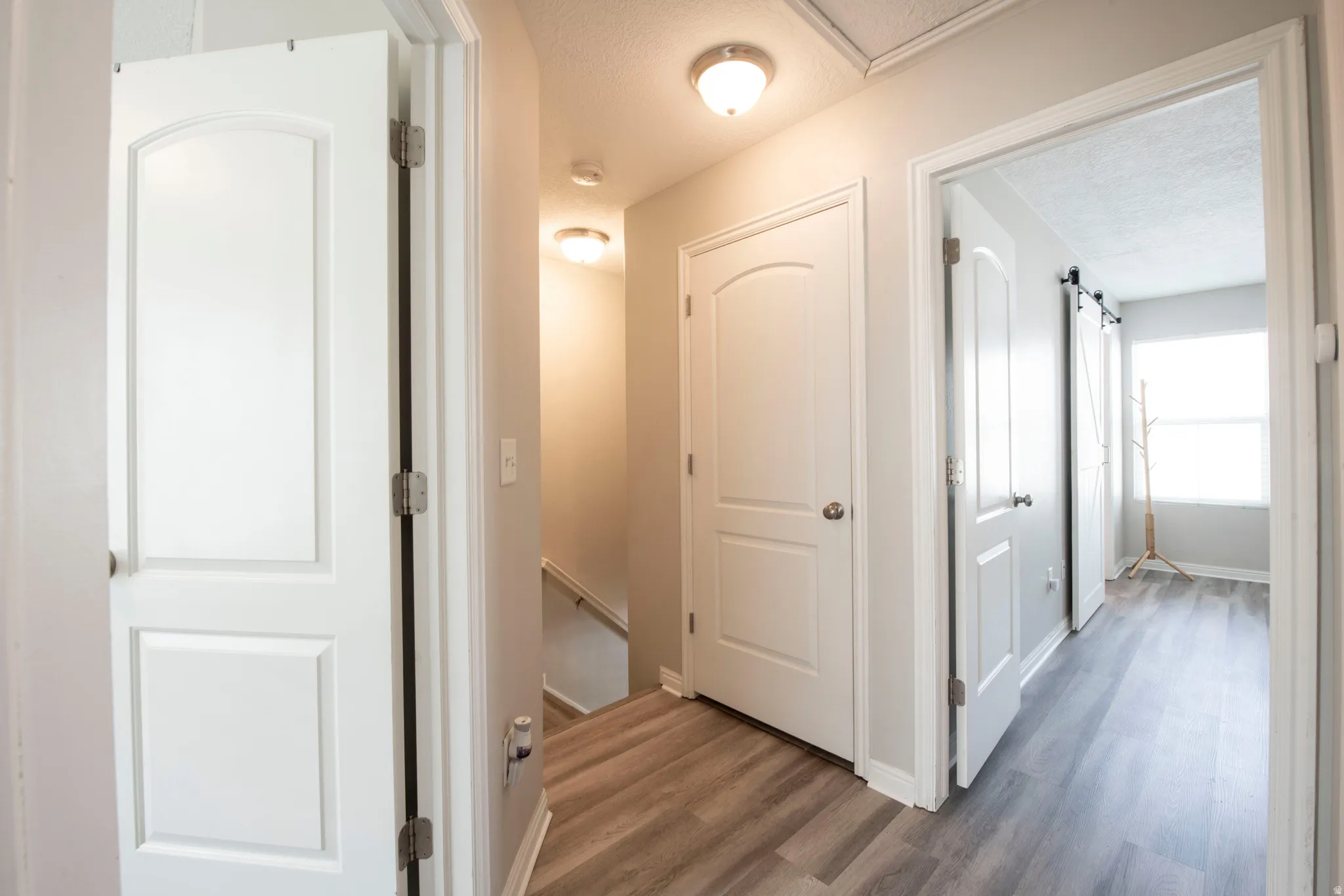 Hallway with a textured ceiling, dark wood finished floors, and an upstairs landing