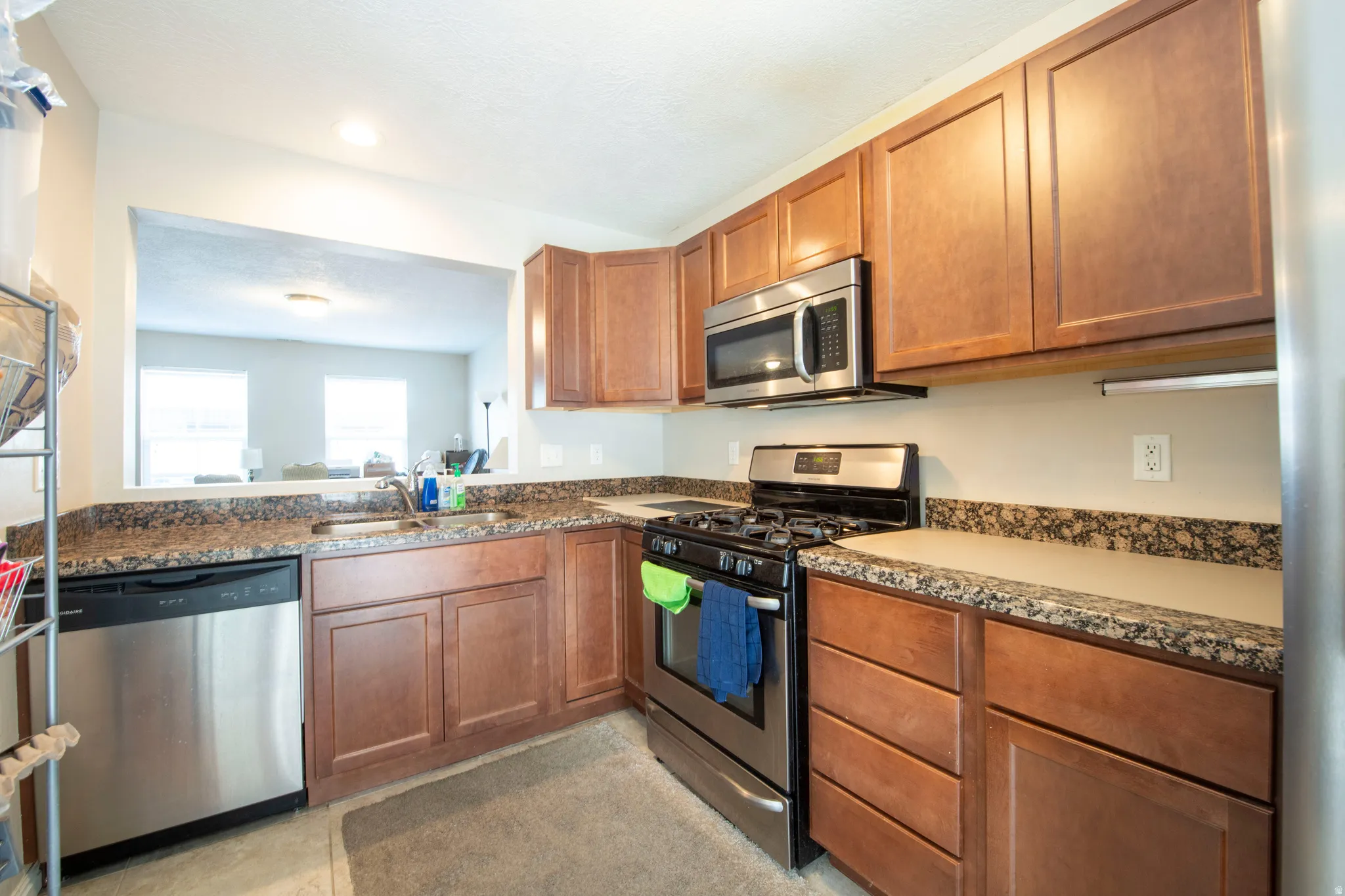 Kitchen with stainless steel appliances, wood finish cabinetry, dark stone countertops, and recessed lighting