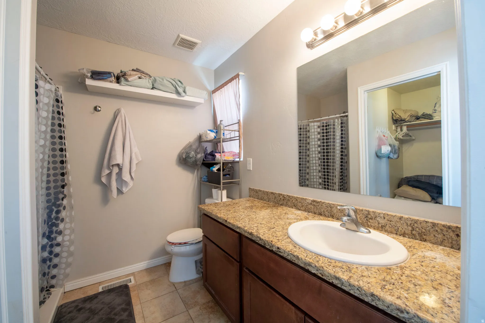 Bathroom with vanity, a shower with shower curtain, light tile patterned floors, and a textured ceiling