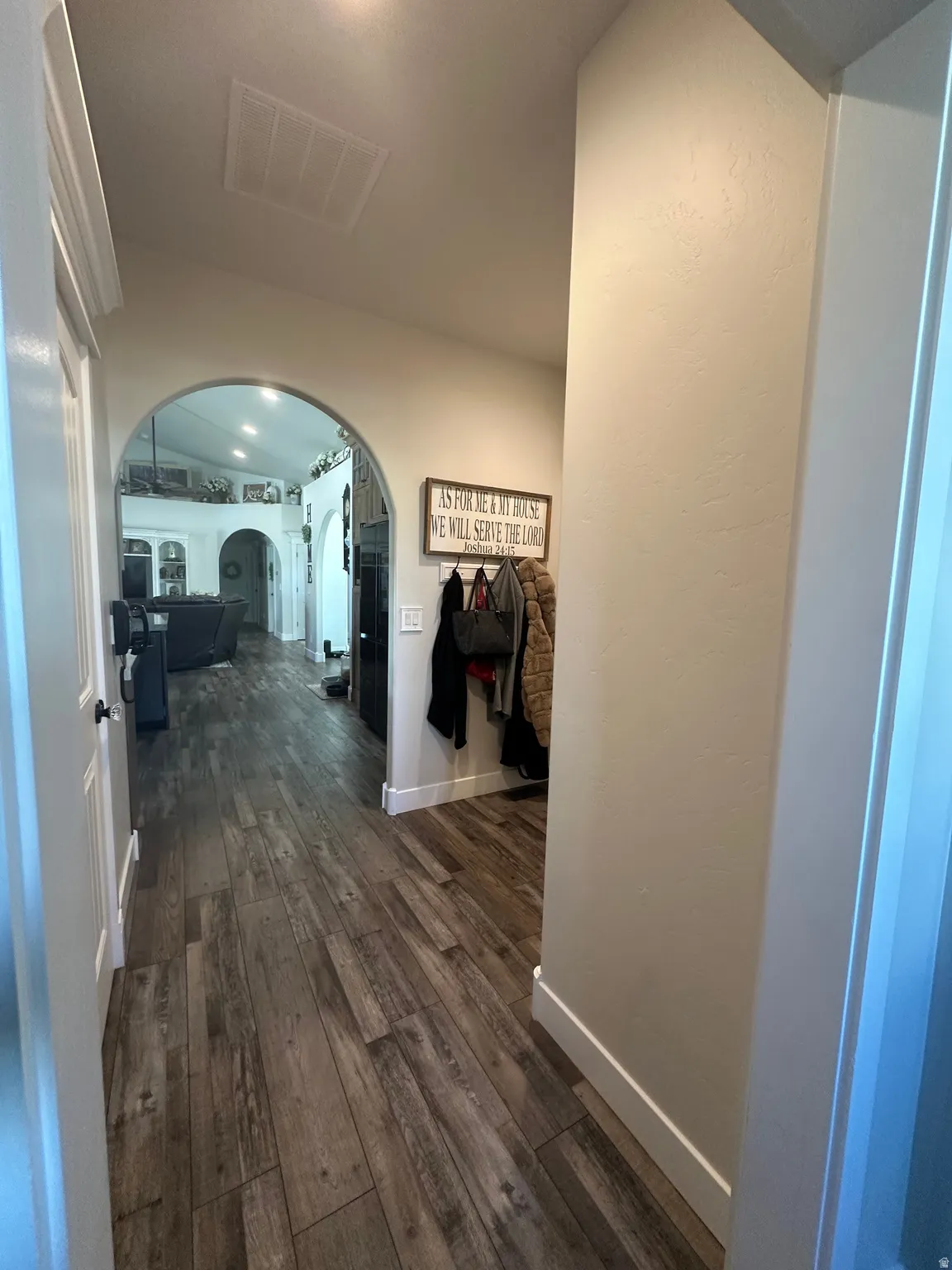 Corridor featuring dark wood-type flooring and arched walkways