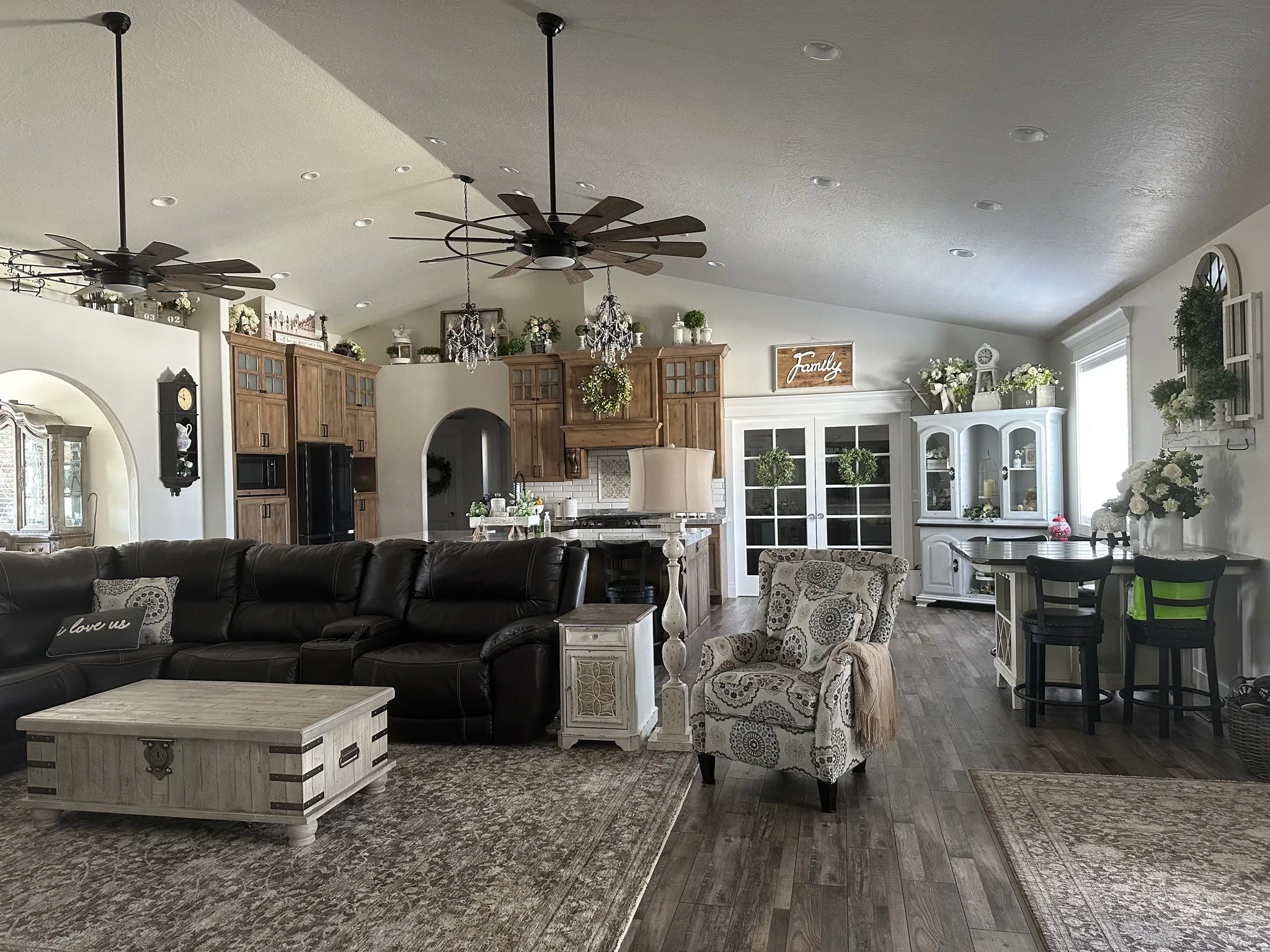 Living area featuring arched walkways, dark wood-style floors, recessed lighting, ceiling fan, and a high ceiling