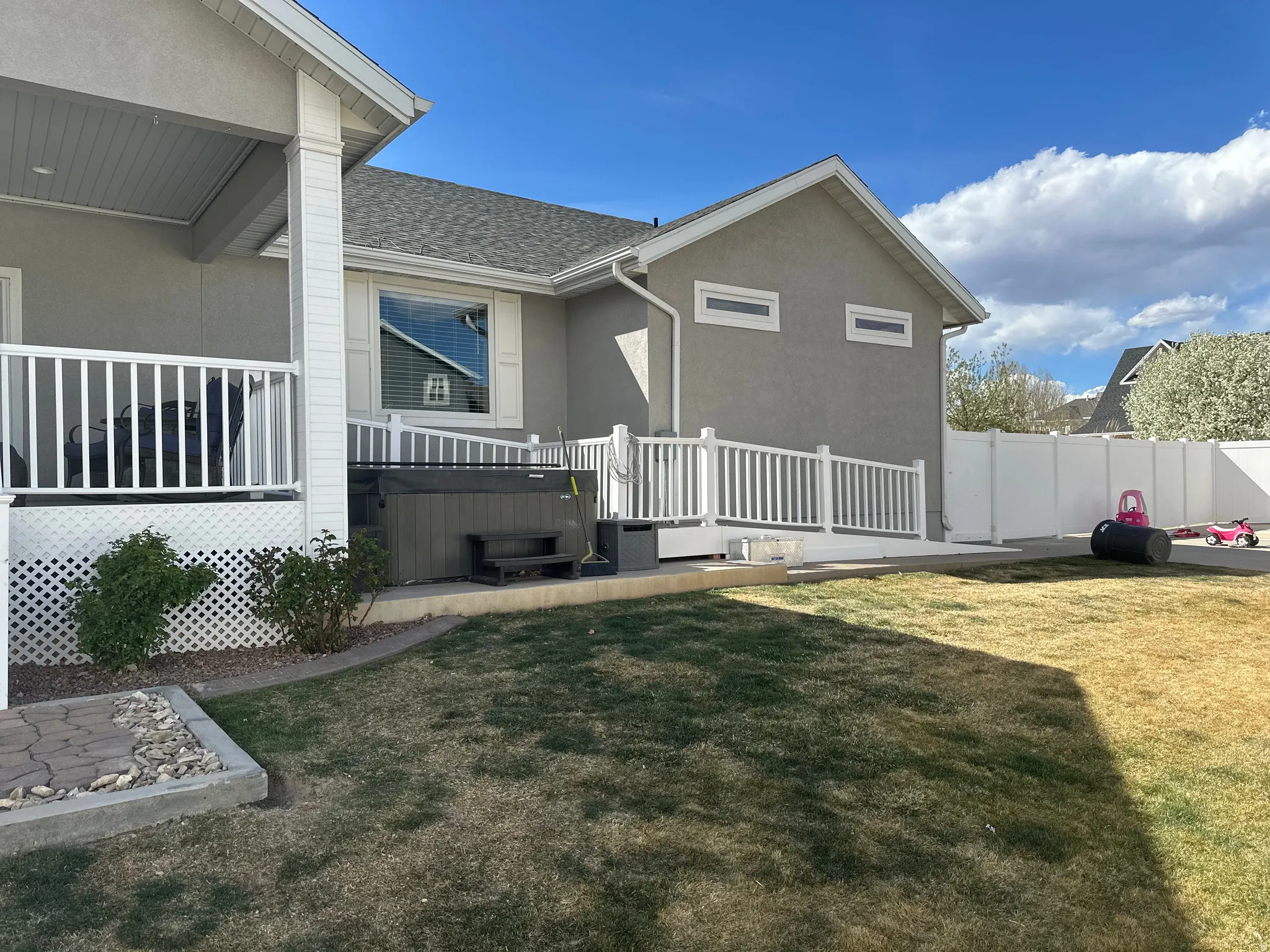 Back of property with a hot tub, stucco siding, roof with shingles, and a deck