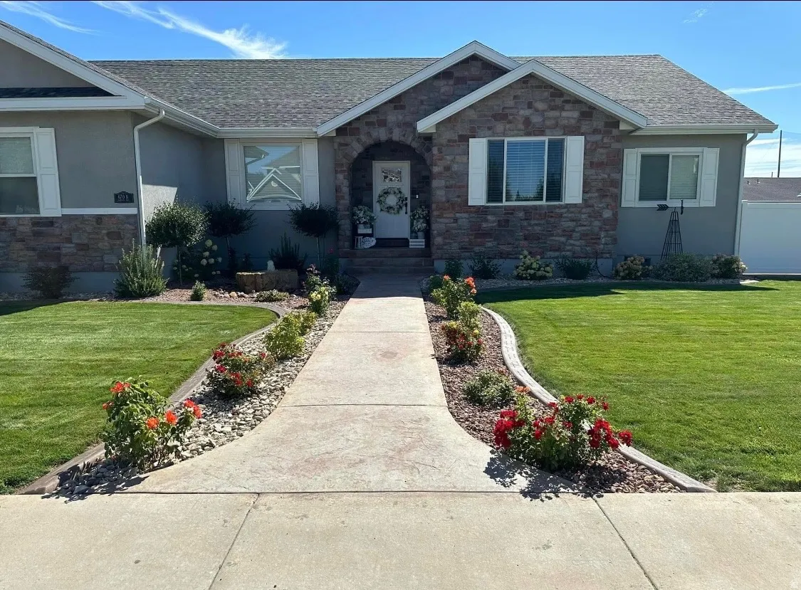 View of front of home with a front yard, stone siding, stucco siding, and a shingled roof
