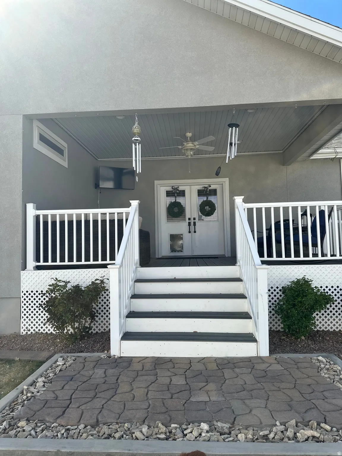 Doorway to property featuring french doors, stucco siding, covered porch, and brick siding