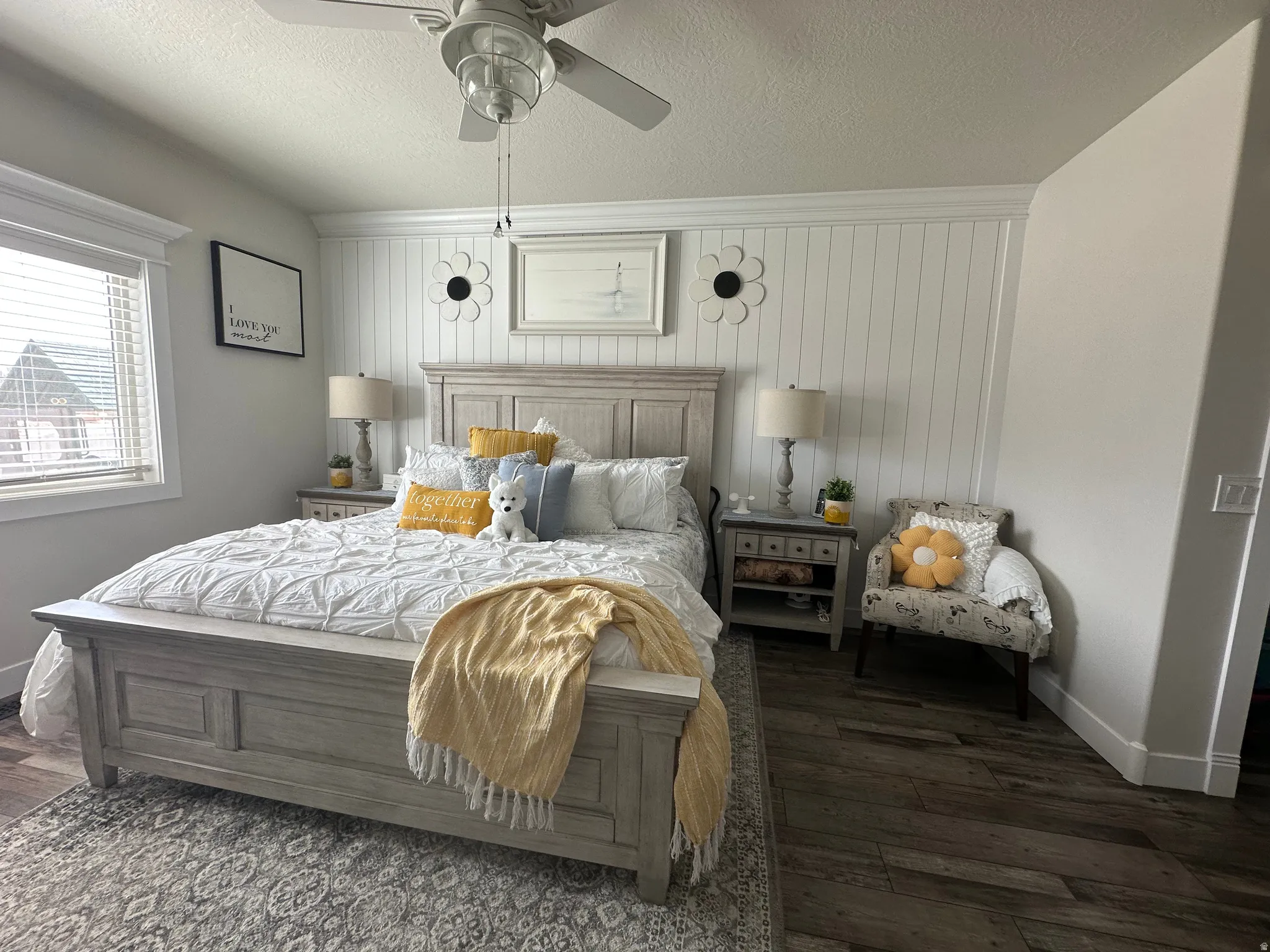 Bedroom featuring dark wood-type flooring, a textured ceiling, a ceiling fan, and wooden walls
