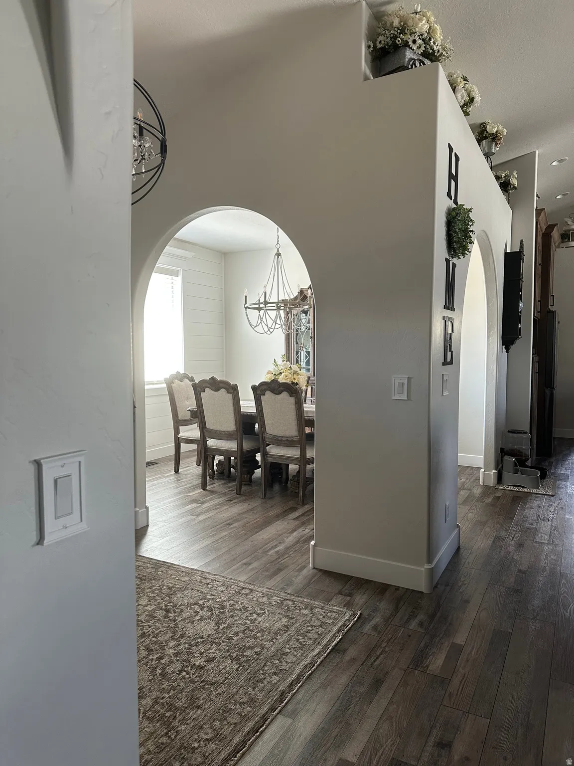 Hallway with arched walkways and dark wood-style flooring