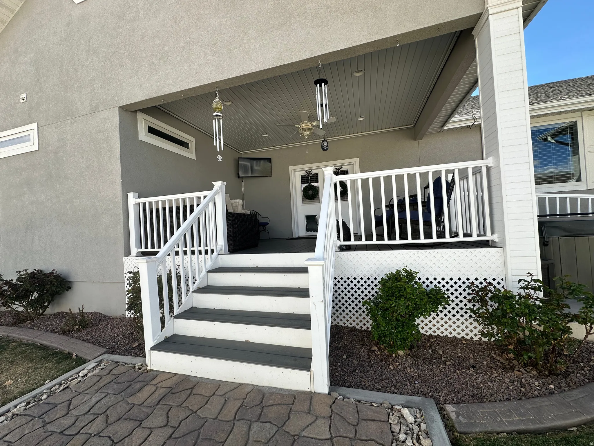 Property entrance with stucco siding, a ceiling fan, and a deck