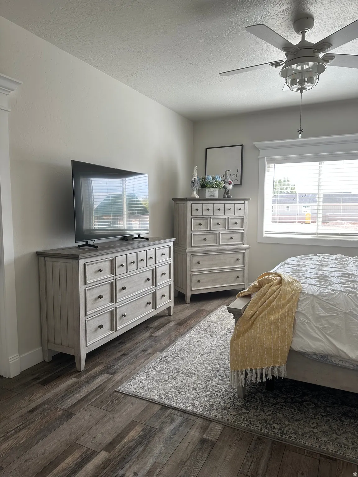 Bedroom with ceiling fan, dark wood-type flooring, and a textured ceiling