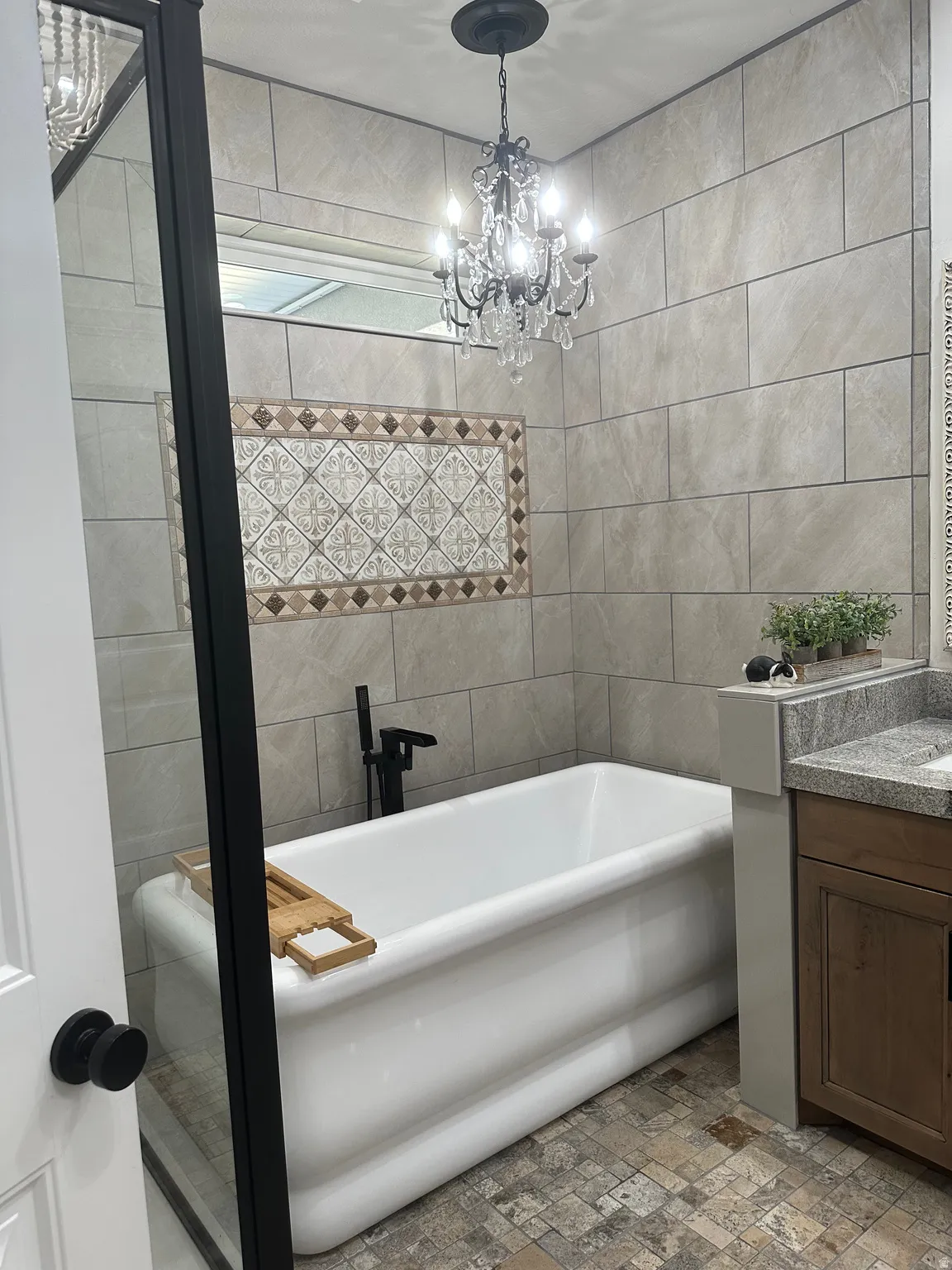 Full bath featuring vanity, a freestanding tub, tile walls, and suspended lighting