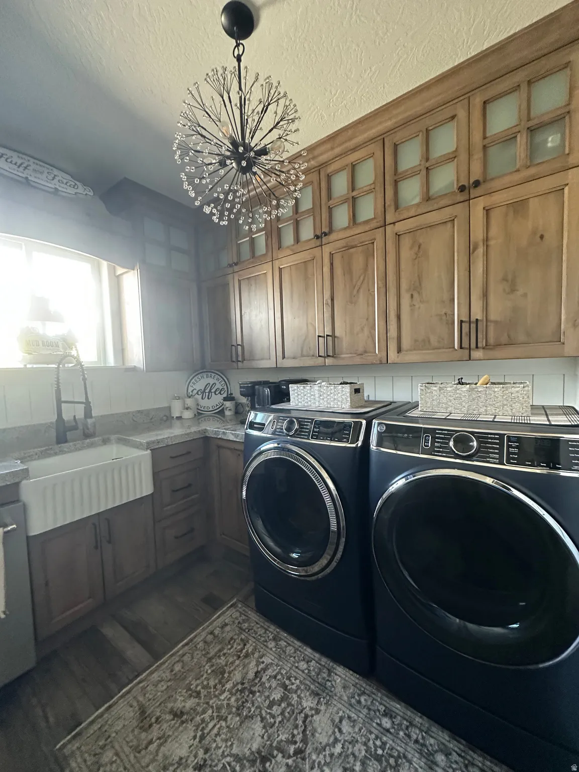 Laundry room featuring a chandelier, a textured ceiling, washing machine and clothes dryer, dark wood finished floors, and cabinet space