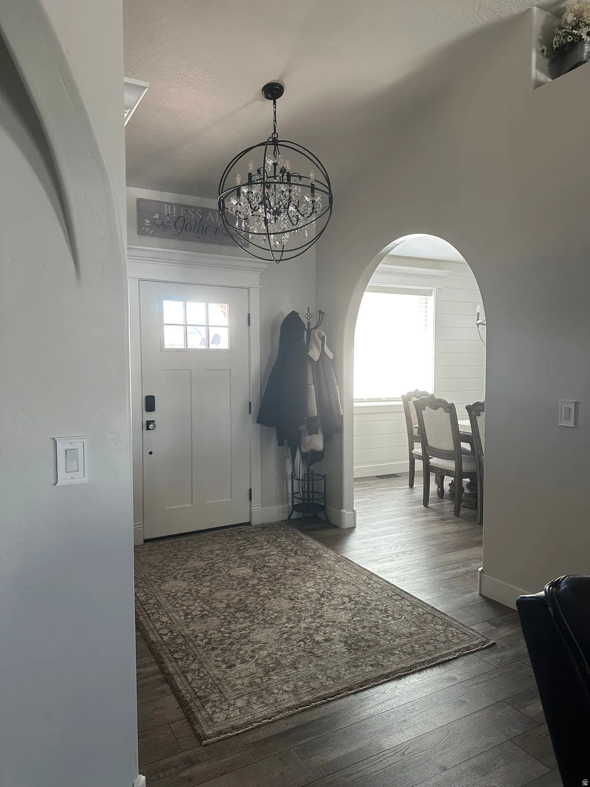 Foyer featuring arched walkways, healthy amount of natural light, hanging lights, and dark wood-style floors