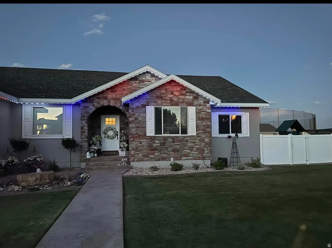 View of front of house with stone siding, roof with shingles, and a gate