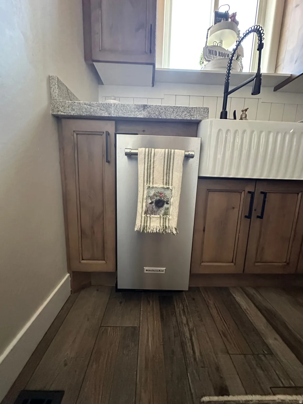 Kitchen view of dark wood-style flooring, wine cooler, light countertops, and wood finish cabinets