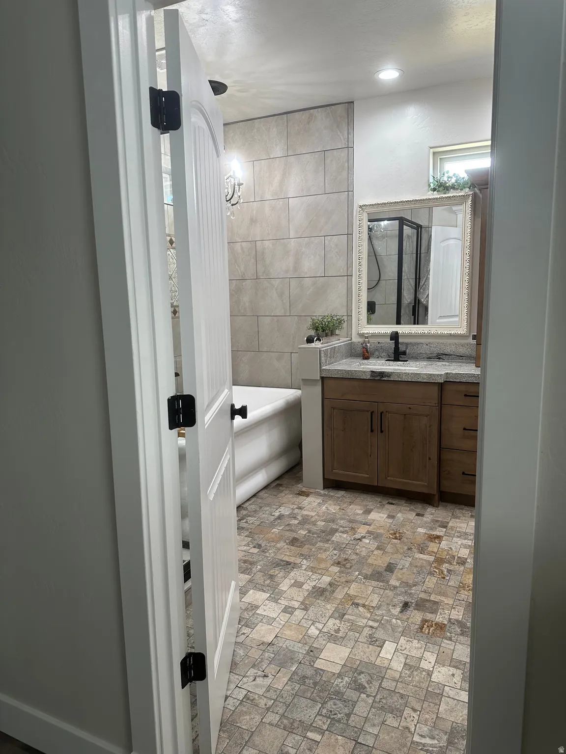Bathroom with a freestanding tub, vanity, and tile walls