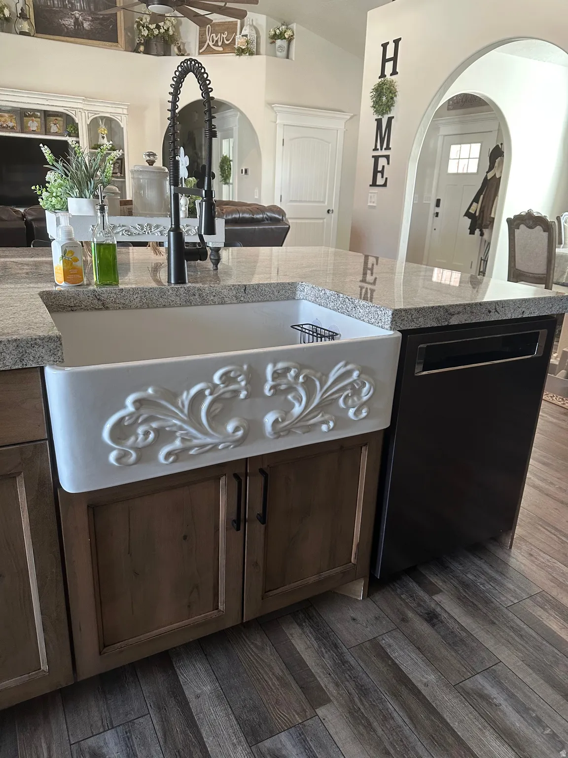 Kitchen with arched walkways, lofted ceiling, dishwasher, and dark wood-style floors
