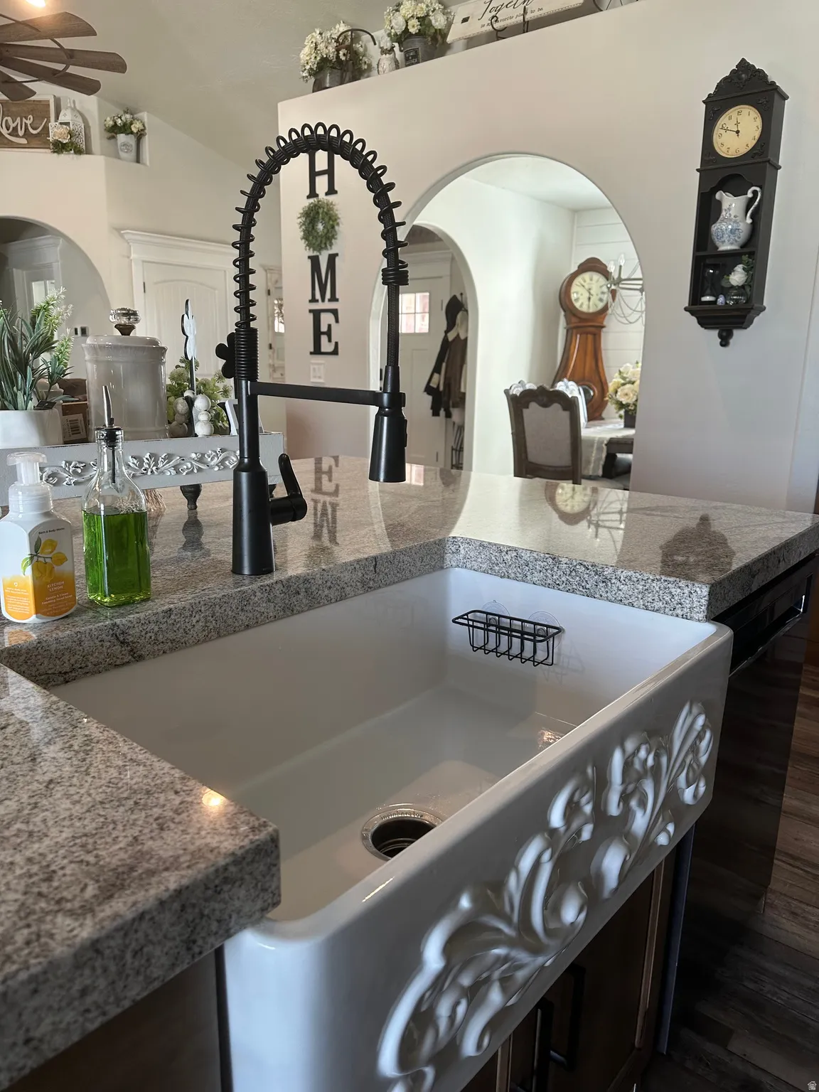 Kitchen view of arched walkways, light stone counters, and a ceiling fan