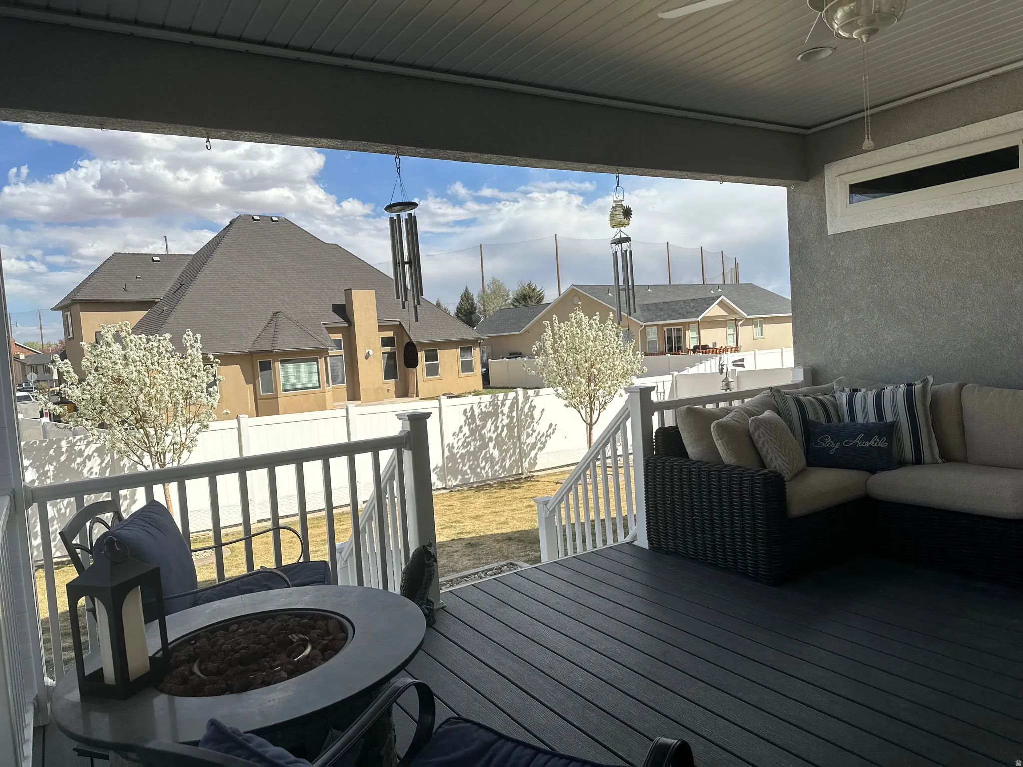 Wooden deck with a residential view, a fenced backyard, an outdoor living space with a fire pit, and a ceiling fan