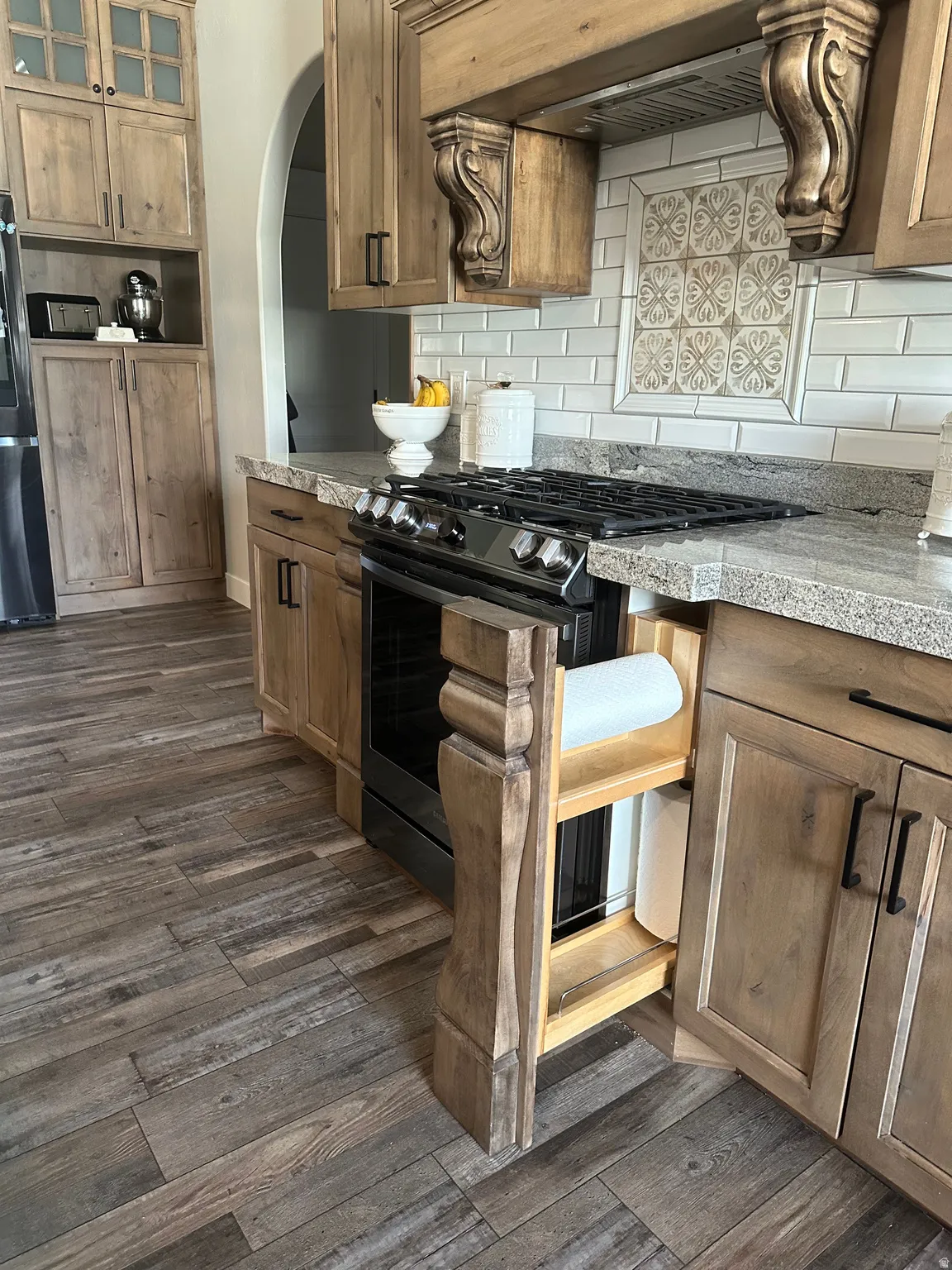 Kitchen with stainless steel appliances, dark wood-style floors, backsplash, and wood finish cabinetry