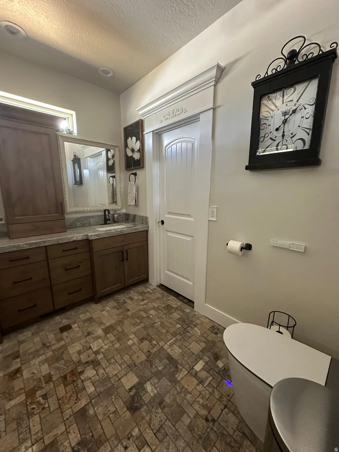 Bathroom featuring vanity, a textured ceiling, and brick patterned floors