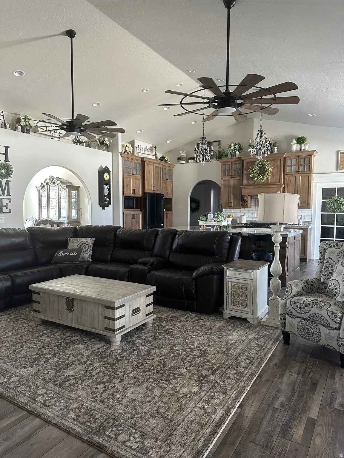 Living area featuring a ceiling fan, arched walkways, and dark wood finished floors