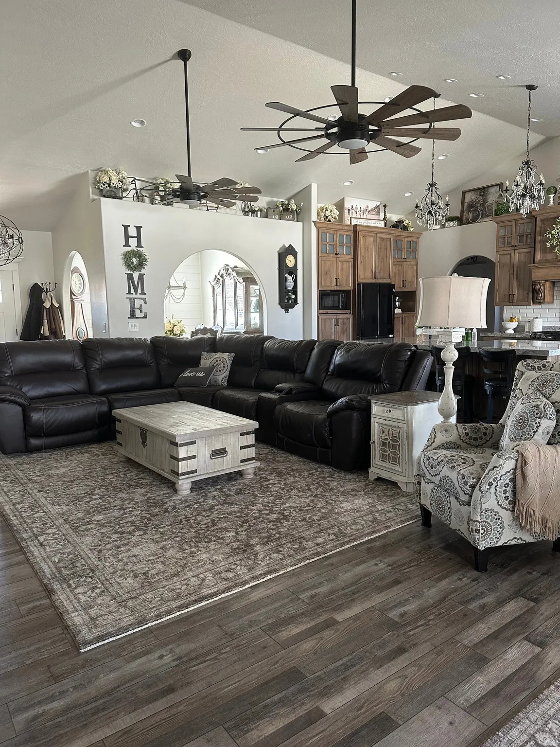 Living room with suspended lighting, ceiling fan, wood finished floors, and vaulted ceiling